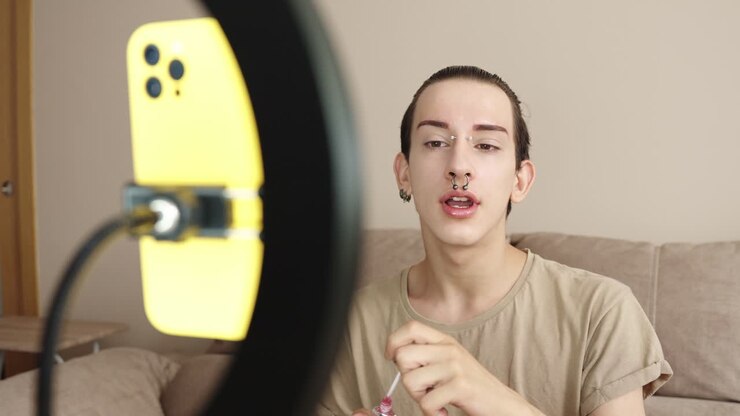 Young adult beauty vlogger applying makeup in front of ring light
