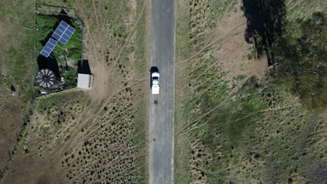 car travelling along a country road past a cattle yard powered by solar panels in outback australia