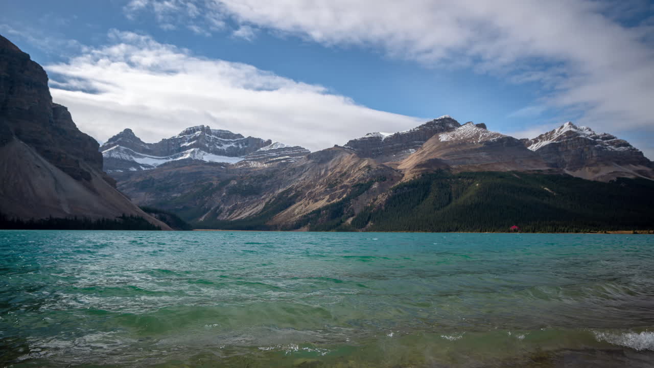 lapso de tiempo, agua alpina del lago bow y nubes sobre las colinas nevadas de las montañas rocosas canadienses en el soleado día de otoño