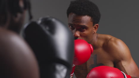 Close-Up-Studio-Shot-Of-Two-Male-Boxers-Wearing-Gloves-Fighting-In-Boxing-Match-Against-Grey-Background-8