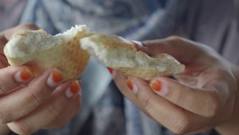 primer plano de una mujer rompiendo un pedazo de pan