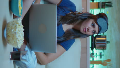 vertical video: woman with eye mask using laptop at night