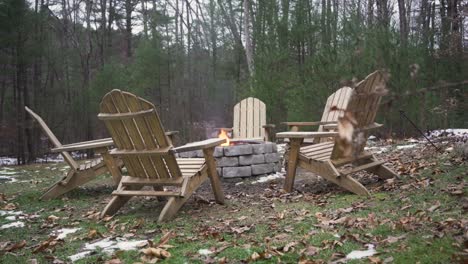 wide view of six empty outdoor chairs around a burning fire pit