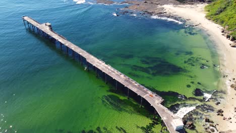 Drohnenaufnahme-Der-Wunderschönen-Malerischen-Kohlenwerft-Bergbaustadtbrücke-Im-Pazifischen-Ozean-Strandblick-Catherine-Hill-Bay-NSW-Australien-3840x2160-4k