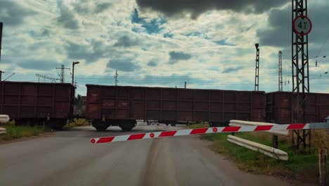 a train passes through a railway crossing with lowered barriers dramatic sky