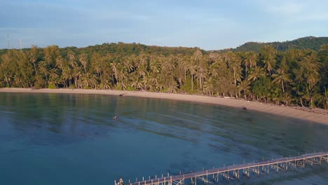 Smooth-aerial-top-view-flight-natural-beach-bay-thailand,-Wooden-walkway-jetty-pier-golden-hour,-lagoon-koh-kood-2022