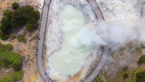 dangerous sulfur smoke rise from sikidang crater in indonesia, aerial top down view