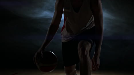 Jugador-De-Baloncesto-Regateando-En-La-Cancha-Con-La-Pelota-En-Una-Habitación-Oscura-Con-Luz-De-Fondo-En-Cámara-Lenta-En-El-Humo