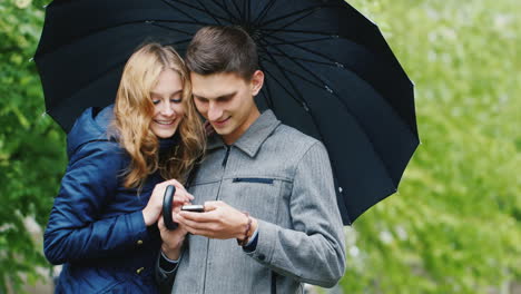 Junges-Paar-Genießt-Ein-Smartphone---Unter-Einem-Regenschirm-Stehend-Der-Regen-Bei-Jedem-Wetter-Verbunden-Hd-V