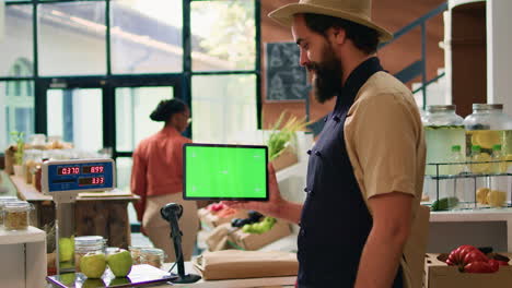 el tendero tiene una tableta de pantalla verde.