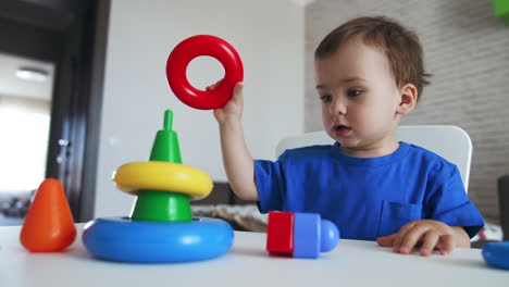 lovely child assembling the colorful pyramid. dark-haired kid puts on the rings from a toy on little hands.