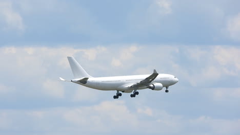 white flying airplane middle of cloudy sky tracking closeup