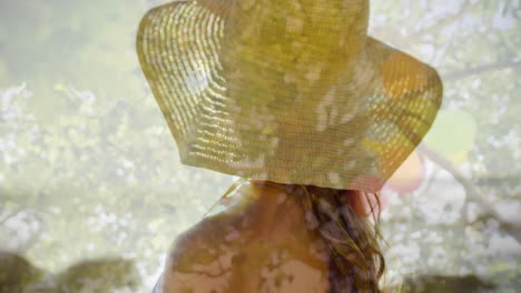 composite video of rear view of woman wearing a hat against tall trees