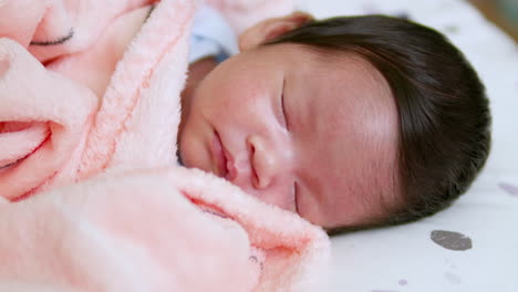 an infant is wrapped in a soft pink blanket, the newborn baby is peacefully sleeping in his mother's arms