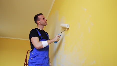 funny craftsman painting walls. cheerful young male worker imitating singing on a paint roller during his work on room renovation.