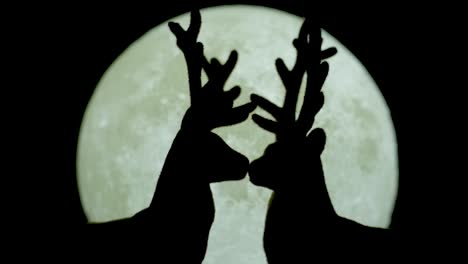 silueta de pareja de renos en miniatura besándose contra el fondo blanco de la luz de la luna