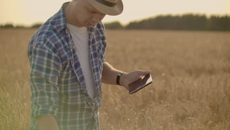 Joven-Agricultor-Sosteniendo-Tableta-En-Campo-De-Trigo