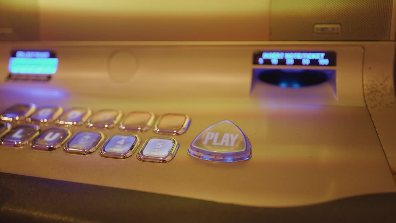 Close-up of illuminated slot machine buttons, hand pressing play, warm ambient casino lighting, static shot