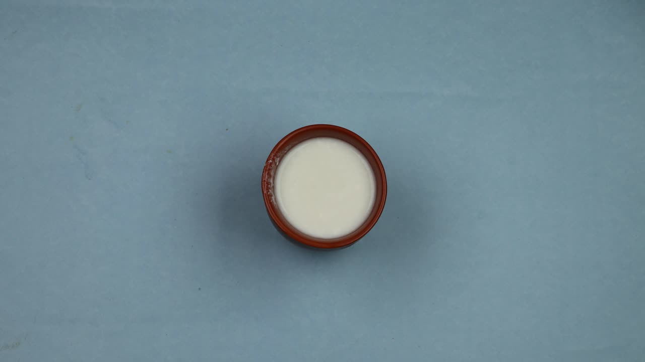 4k uhd stop motion relleno de vidrio de barro con leche fresca sobre fondo de mesa azul