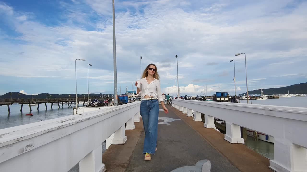 Donna che passeggia su un molo con una bevanda