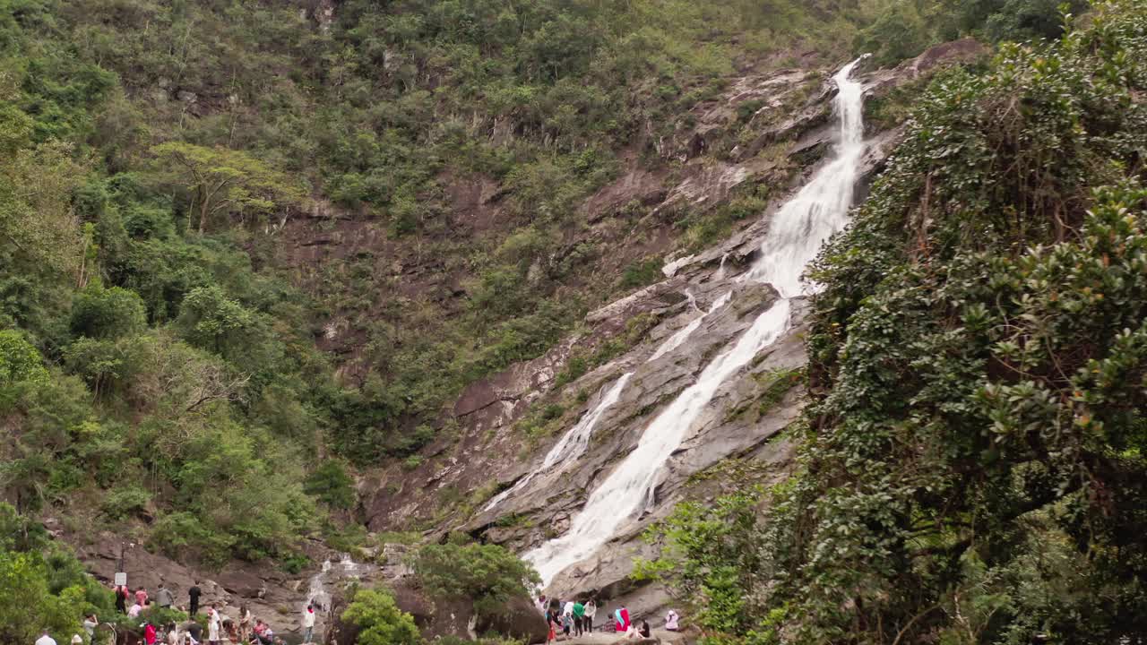 vista aérea de la cascada de montaña y numerosos turistas reunidos en la parte inferior