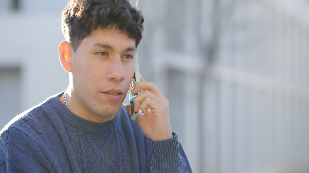 Cheerful young man sitting and speaking on smartphone