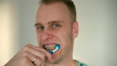 close up of young man with braces brushing his teeth in slow motion