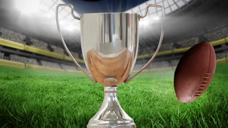 Animation-of-silver-cup-with-rugby-balls-in-rugby-field-sports-stadium