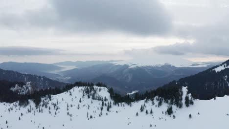 Snow-covered-ciucas-mountains-with-cloudy-skies,-aerial-view