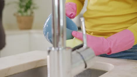 Midsection-of-biracial-sisters-cleaning-in-kitchen,-in-slow-motion