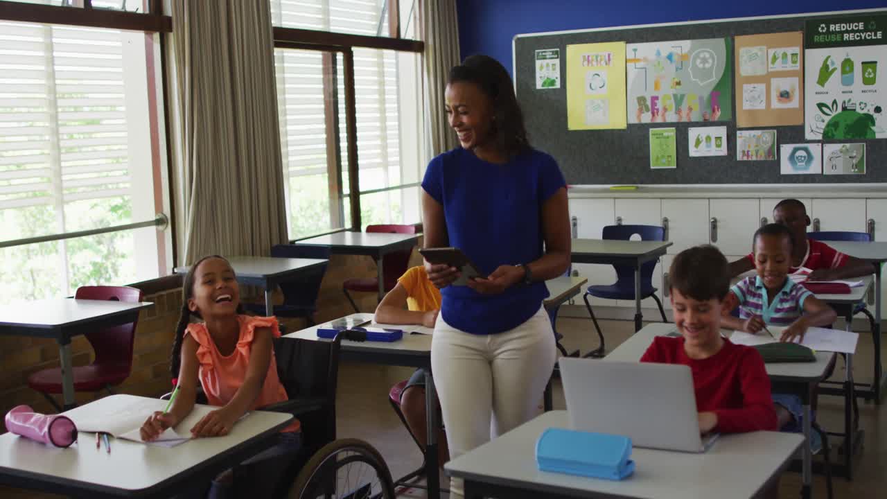 Happy diverse female teacher with tablet and schoolchildren during lesson in classroom