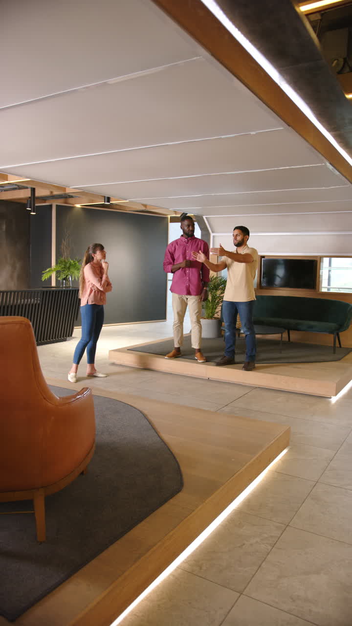 Vertical video: Discussing project details, three colleagues collaborating in modern office space