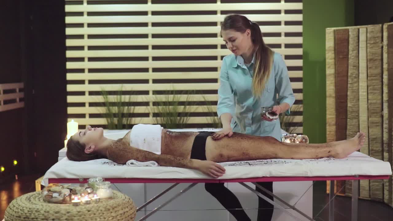 Woman receiving a body scrub massage at a spa