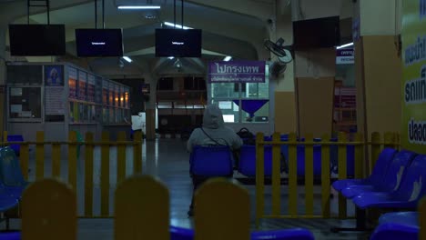 empty bus station terminal at night with only one person waiting for departure, thailand