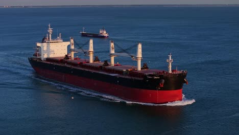 a drone view of the red tomini unity ship sailing in the waters of holland transporting cargo