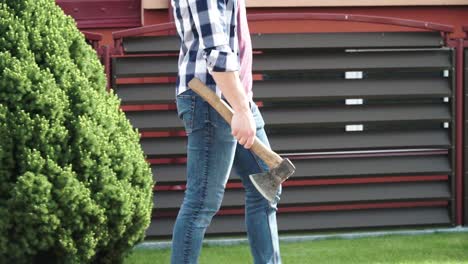 a-young-man-with-blue-jeans-and-a-blue-shirt-is-walking-with-the-axe-in-his-hand