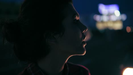 thoughtful young woman smokes a cigarette in the city at night. close up. slow motion shot