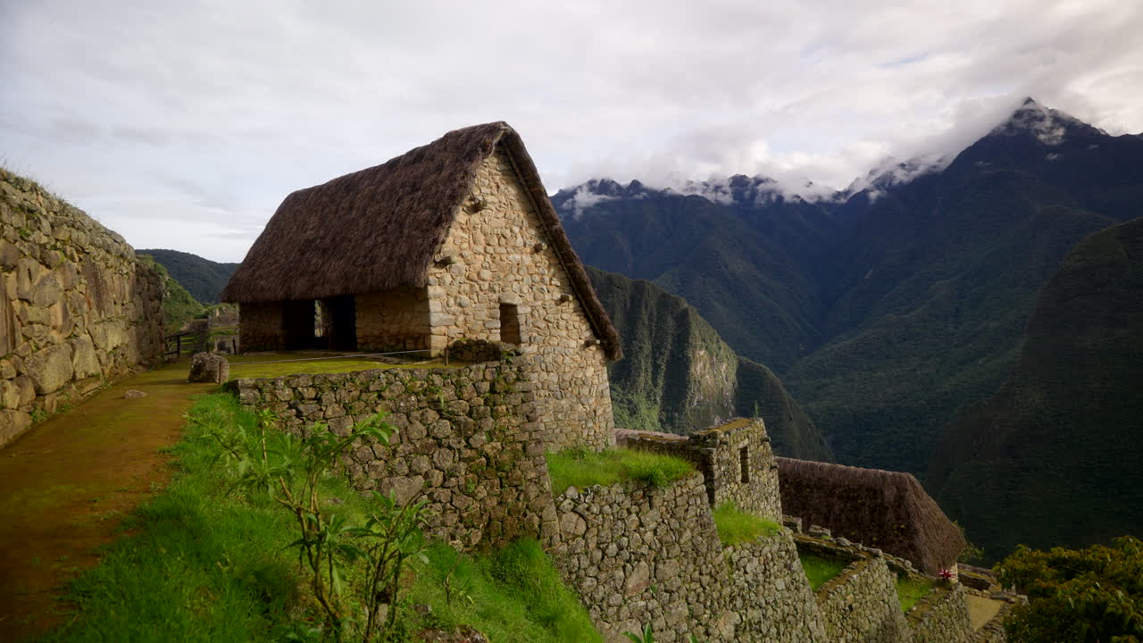 Quiet view of the ancient Inca stone structures at Machu Picchu in Peru, showing terraces, walls, and dramatic Andean mountains under shifting clouds during an idyllic moment
