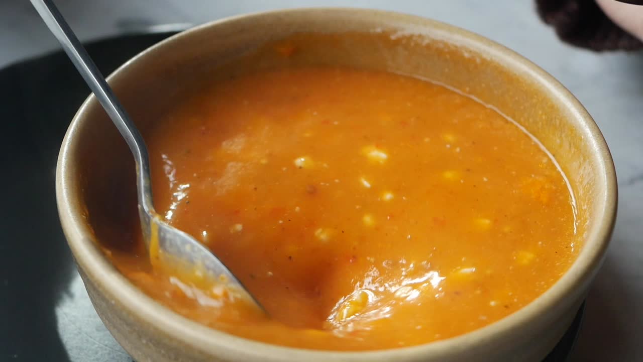 Close-up de Deliciosa Sopa Alaranjada Sendo Mexida com uma Colher