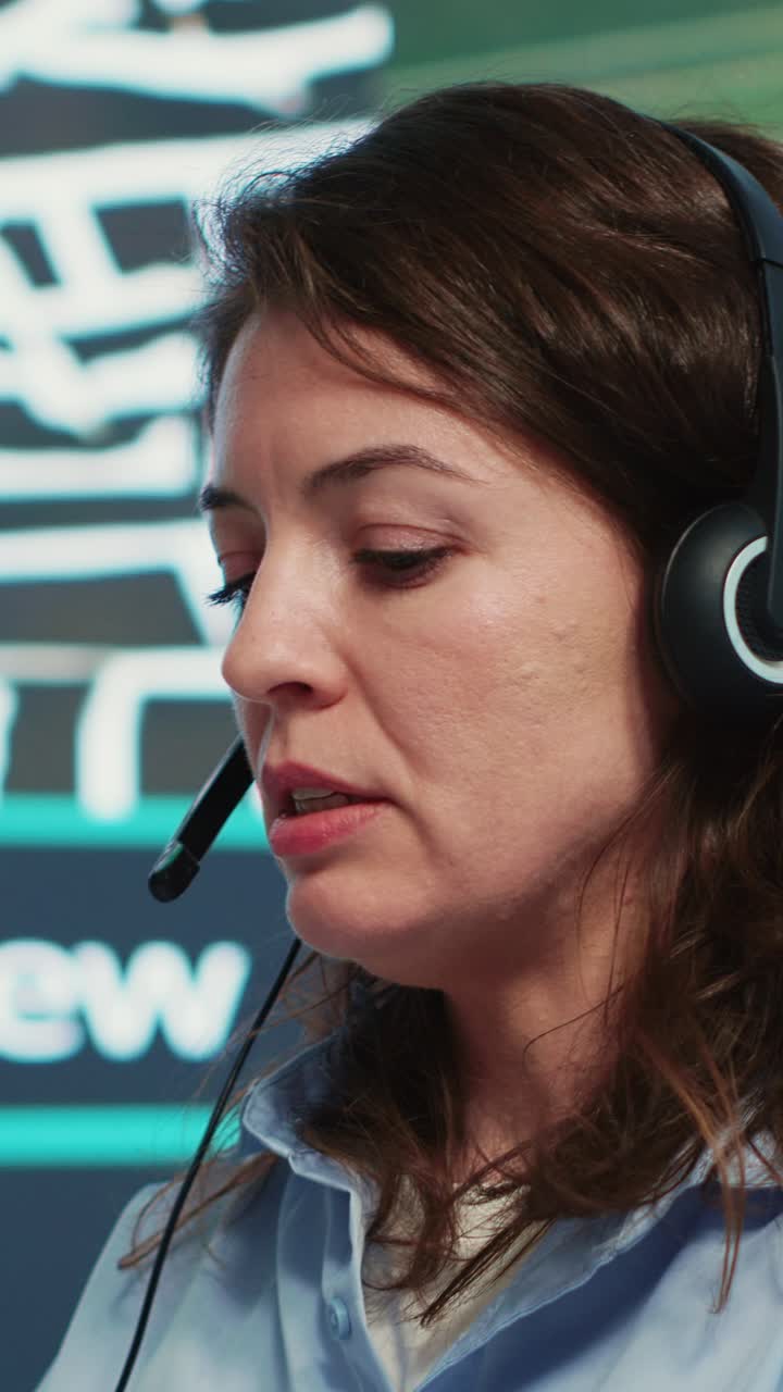 Profesjonell kvinne med headset som snakker og skriver ved pulten