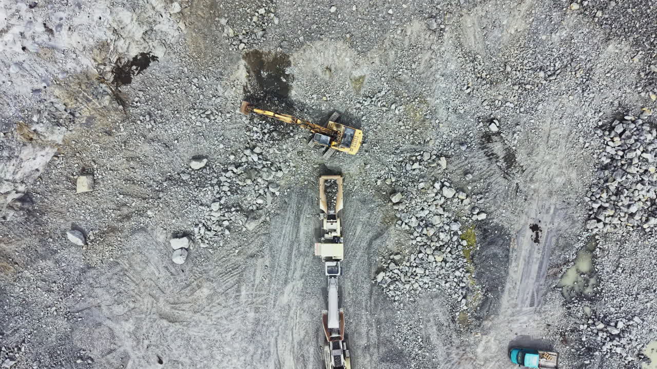 Large granite quarry shows heavy machinery at work crushing and extracting rock near a construction site in a sunny environment during midday operations