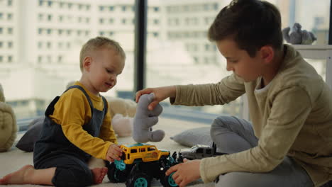 Süße-Brüder,-Die-Im-Spielzimmer-Spielzeug-Auf-Autos-Legen.-Geschwister-Spielen-Auf-Dem-Teppich