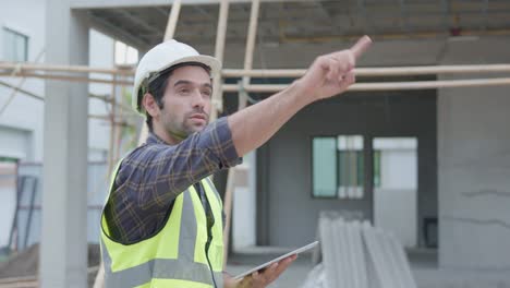 professional male civil engineer or architect wear safety helmet. while engineer, inspector walking use tablet technology for check list building project on construction site. real estate concept.