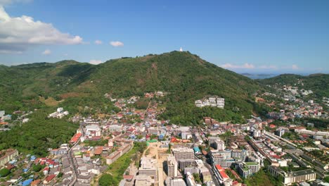 buildings of karon beach town with the big buddha on the top of the hill in tropical phuket thailand on a sunny summer day