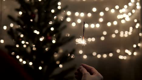 mujer sosteniendo chispas con luces de árbol de navidad en una fiesta