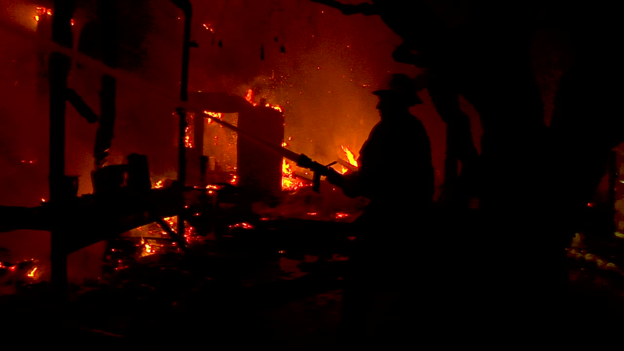 벤츄라와 산타 바바라의 토마스 화재 동안 소방관이 실루엣으로 서서 거대한 산비탈 화재와 싸웁니다.