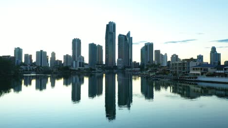 Mirror-image-across-still-canal-waters-at-sunrise,-looking-towards-Surfers-Paradise