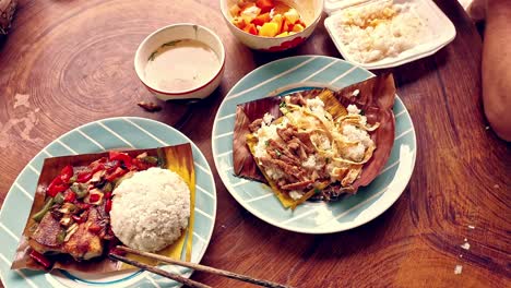 Overhead-view-of-eating-authentic-traditional-khmer-food-for-breakfast-of-Trei-boeng-kanh-chhet-or-spicy-fried-fish-and-Bai-sach-chrouk-or-pork-with-steamed-rice