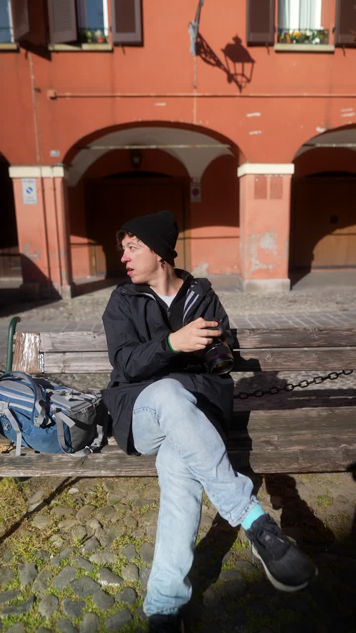 Photographer sitting on a bench in a city square