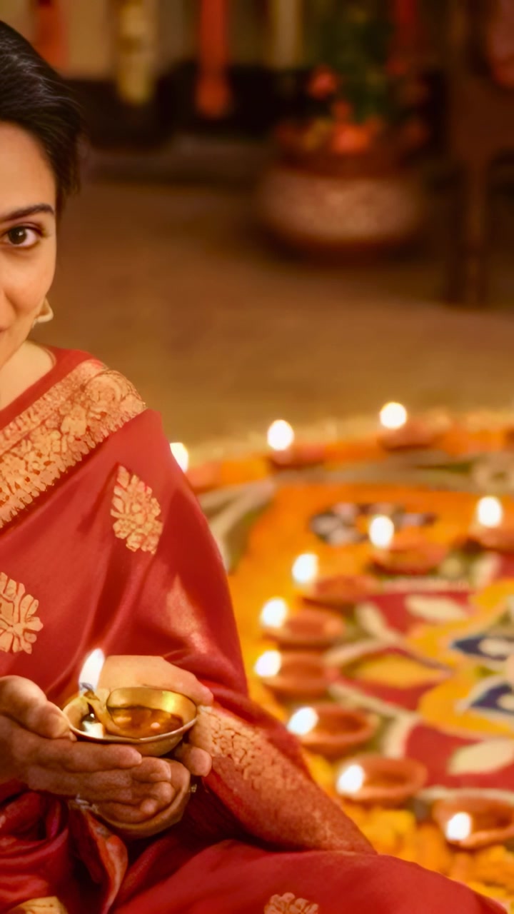Video verticale: Donna in sari che tiene una diya a coppa durante una puja domestica su un rangoli, con la telecamera che si allontana e spazio per il testo